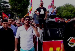 Demonstration, among the people a man with a microphone beside the vehicle with the loudspeakers
